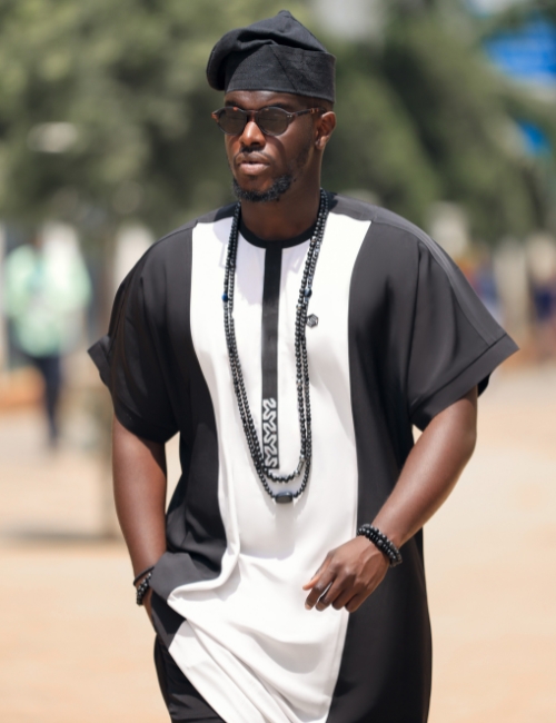 man wearing black-and-white Soso Africa danshiki while walking outdoors.